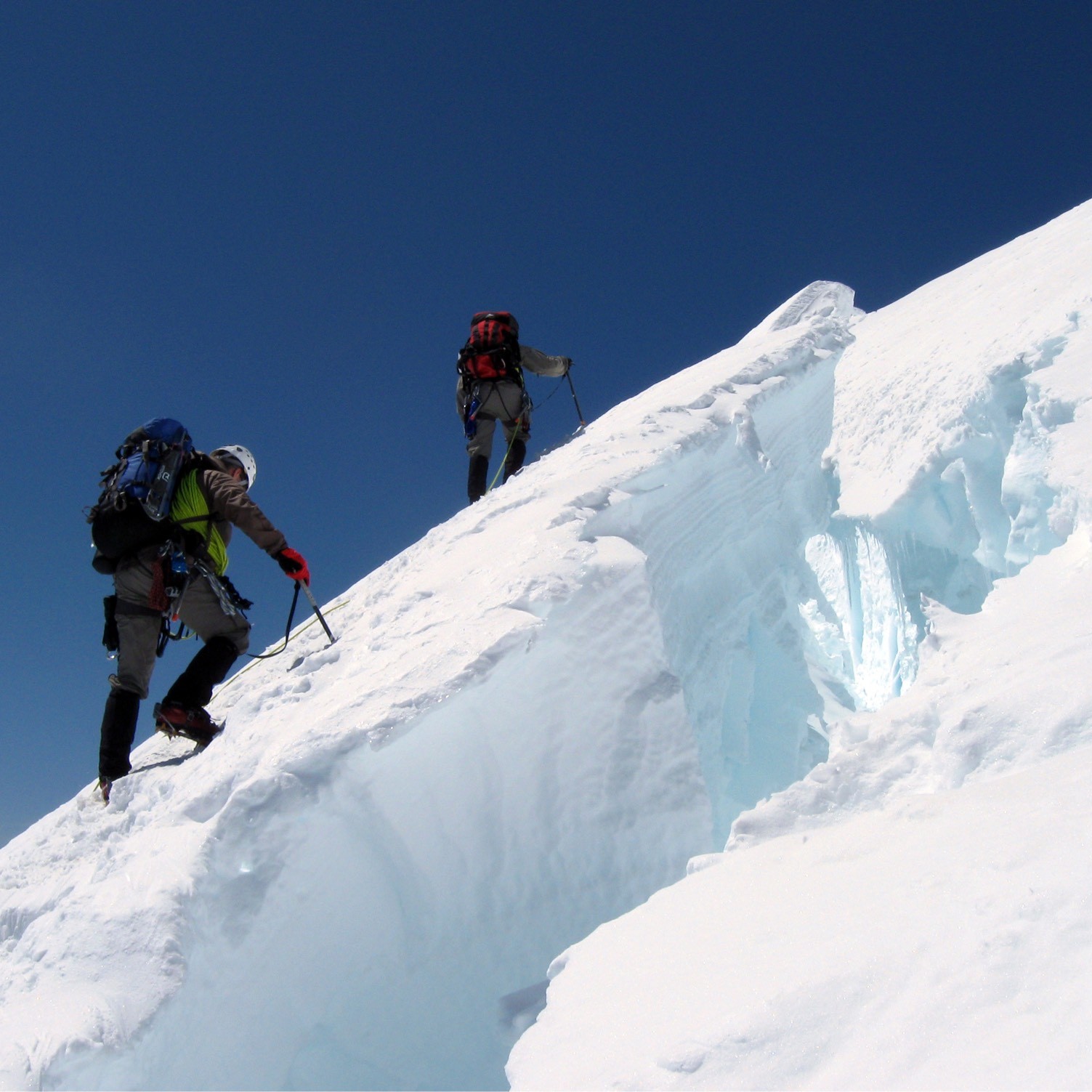 Mountain climbers ascending a steep, snow-covered slope.