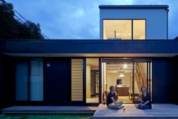 Two people on the patio of a modern home at twilight