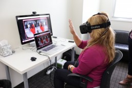 Woman wearing VR Headset interacts with a virtual user interface.