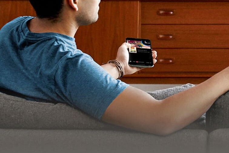 Young man sitting on a couch using a Chromecast to watch TV