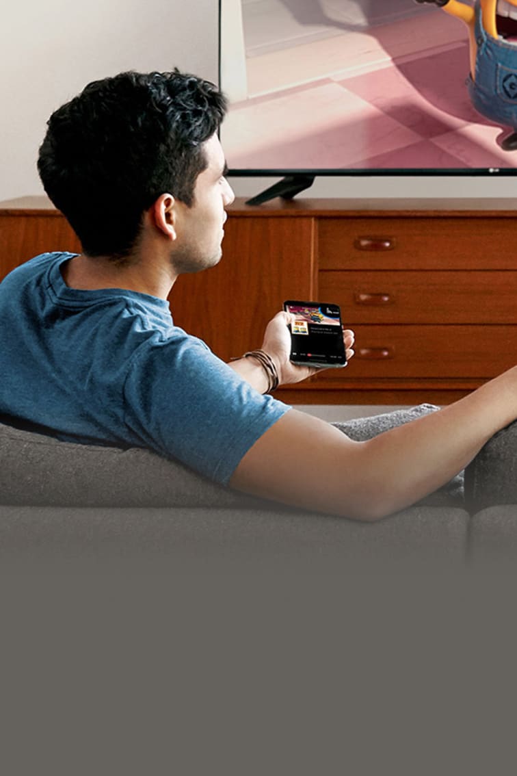 Young man sitting on a couch using a Chromecast to watch TV
