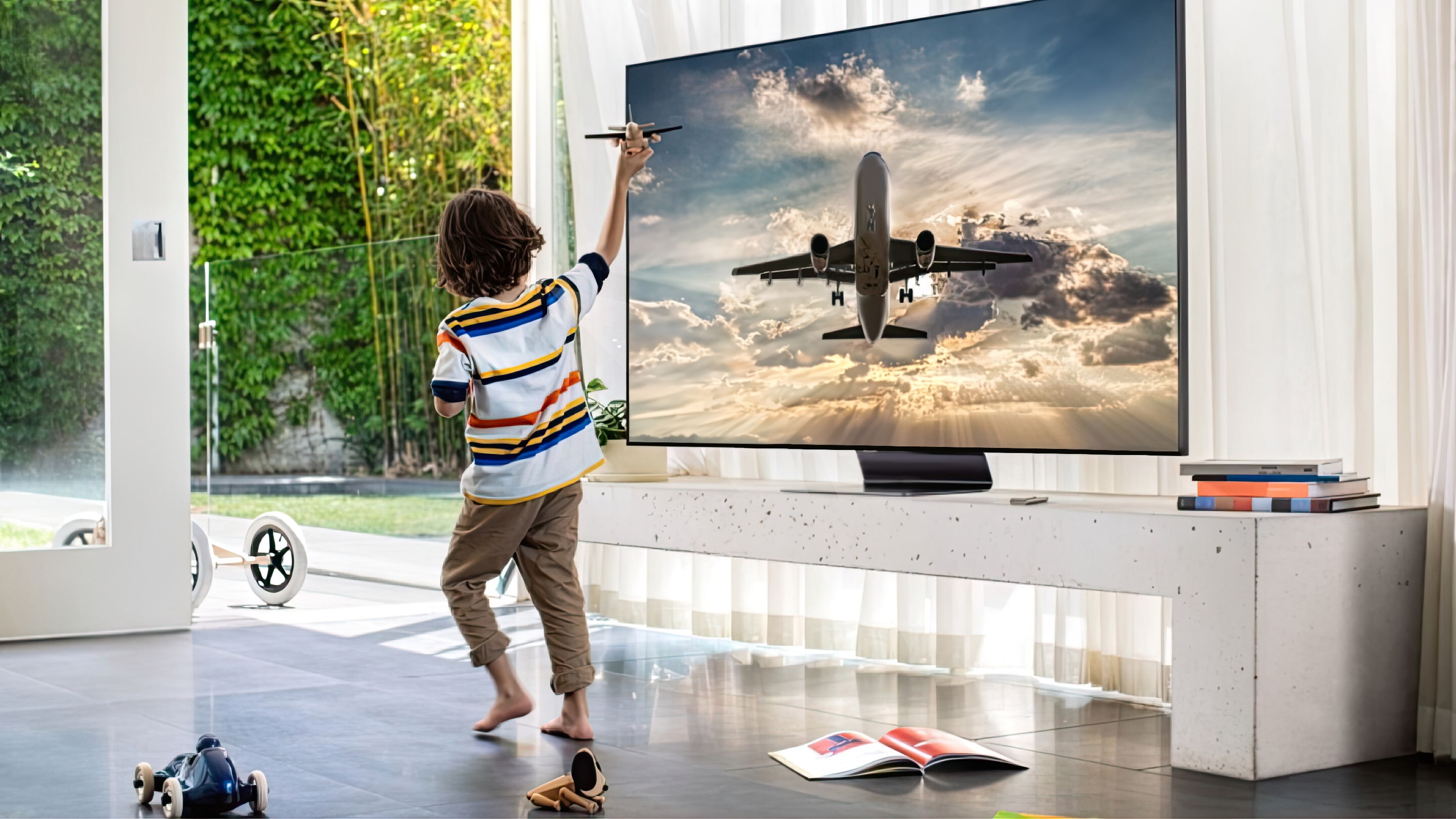 Child plays with a toy airplane in front of an image of a plane taking off