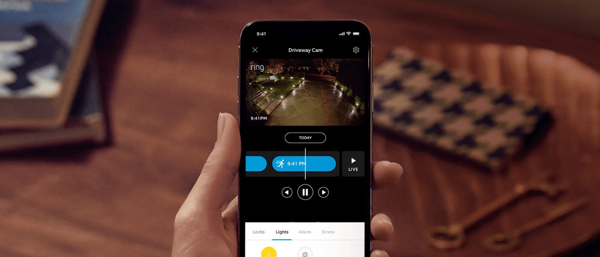 Person holding a phone displaying the Ring smart home app.